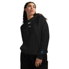 Woman wearing Under Armour x Signature embroidered hoodie in black, showcasing the luxuriously soft fleece and relaxed fit.
